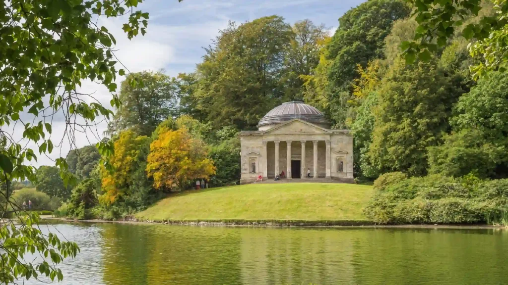 Tempio neopalladiano di Stourhead in lontananza immerso nel verde e con un laghetto davanti 