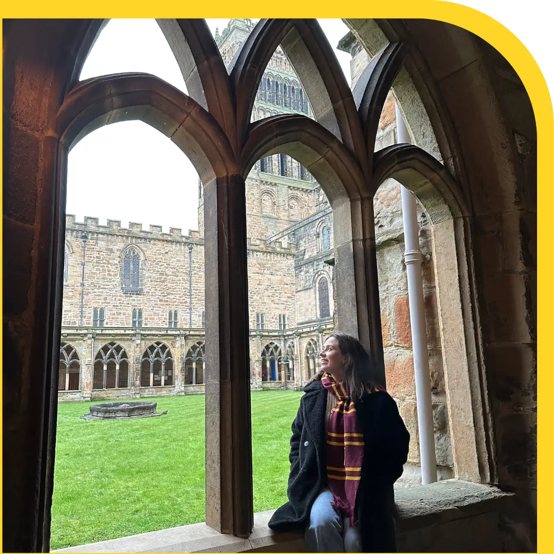 ragazza vestita di nero e con la sciarpa rossa e gialla (colori di Grifondoro) con i chiostri sul retro.
