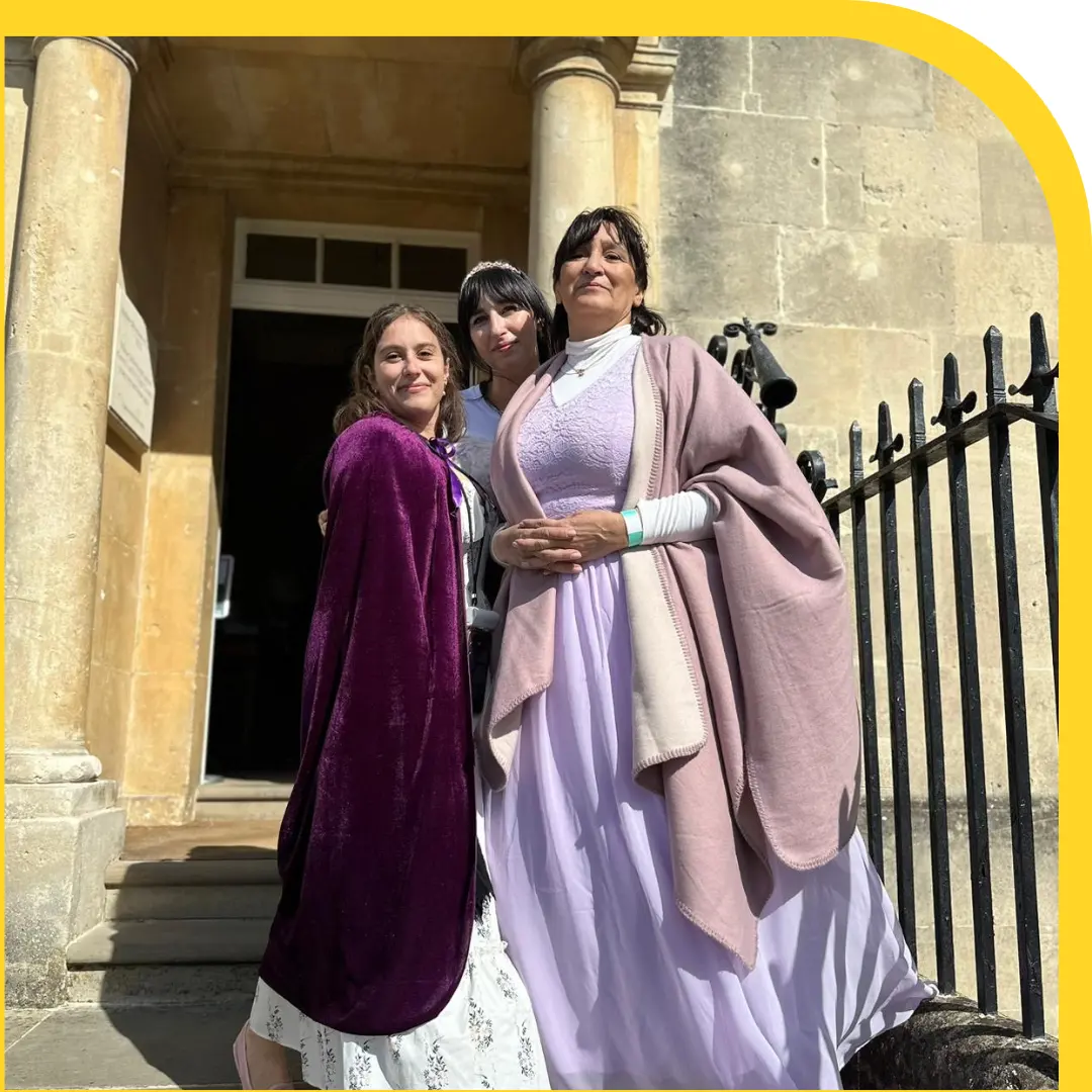 tre donne castane su una scalinata vestite in abiti regency tra il viola e il rosa