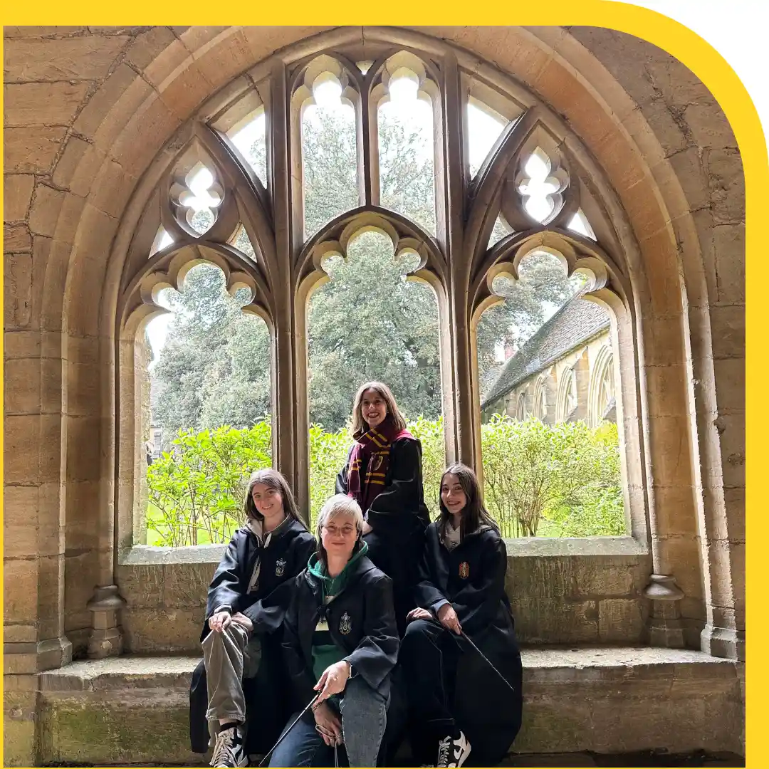 quattro persone vestiti con toghe e bacchette ognuna di una casa di hogwarts in posa in un chiostro medievale